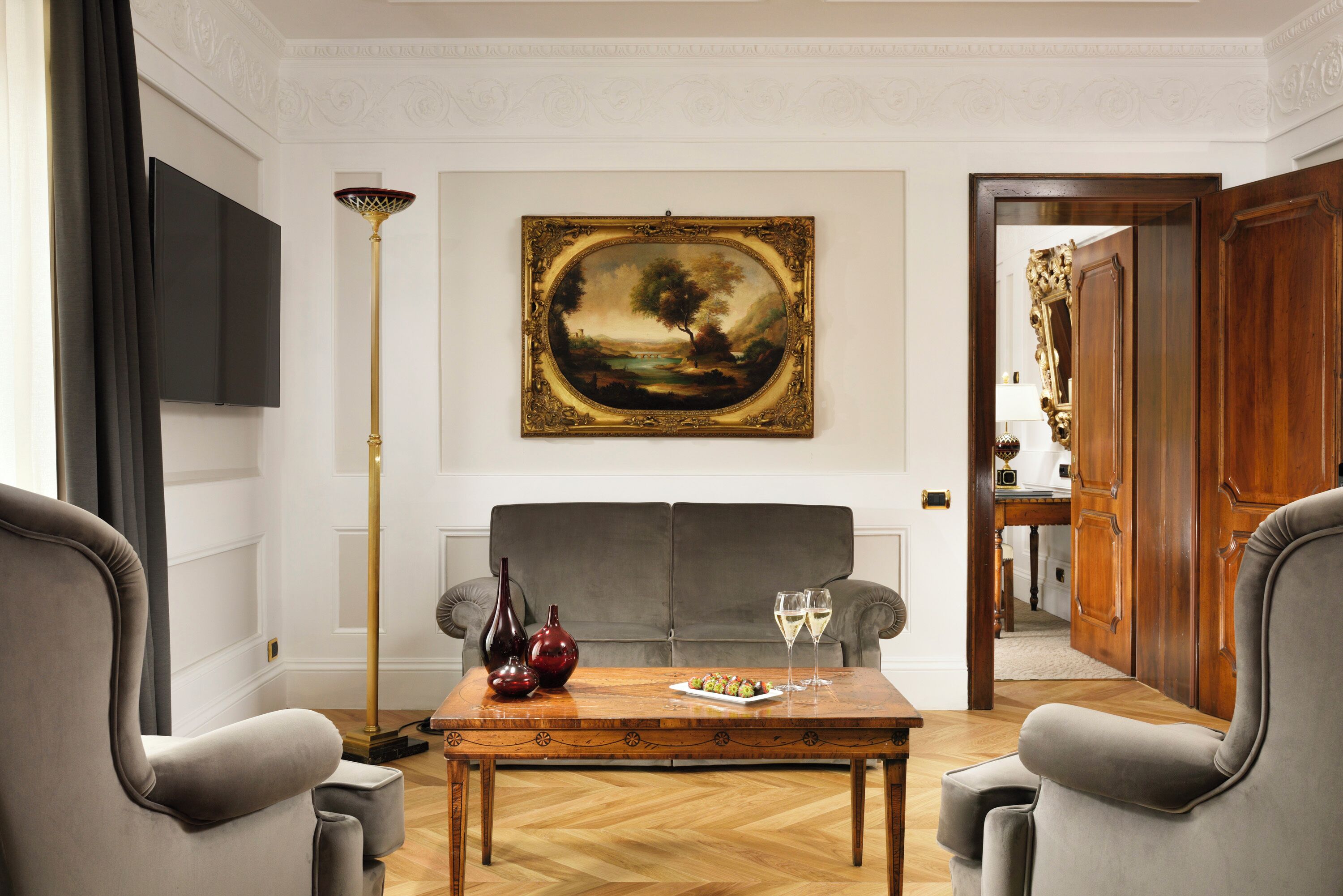 A room with a sofa, a coffee table with decorative items, a painting, and a door leading to another room.