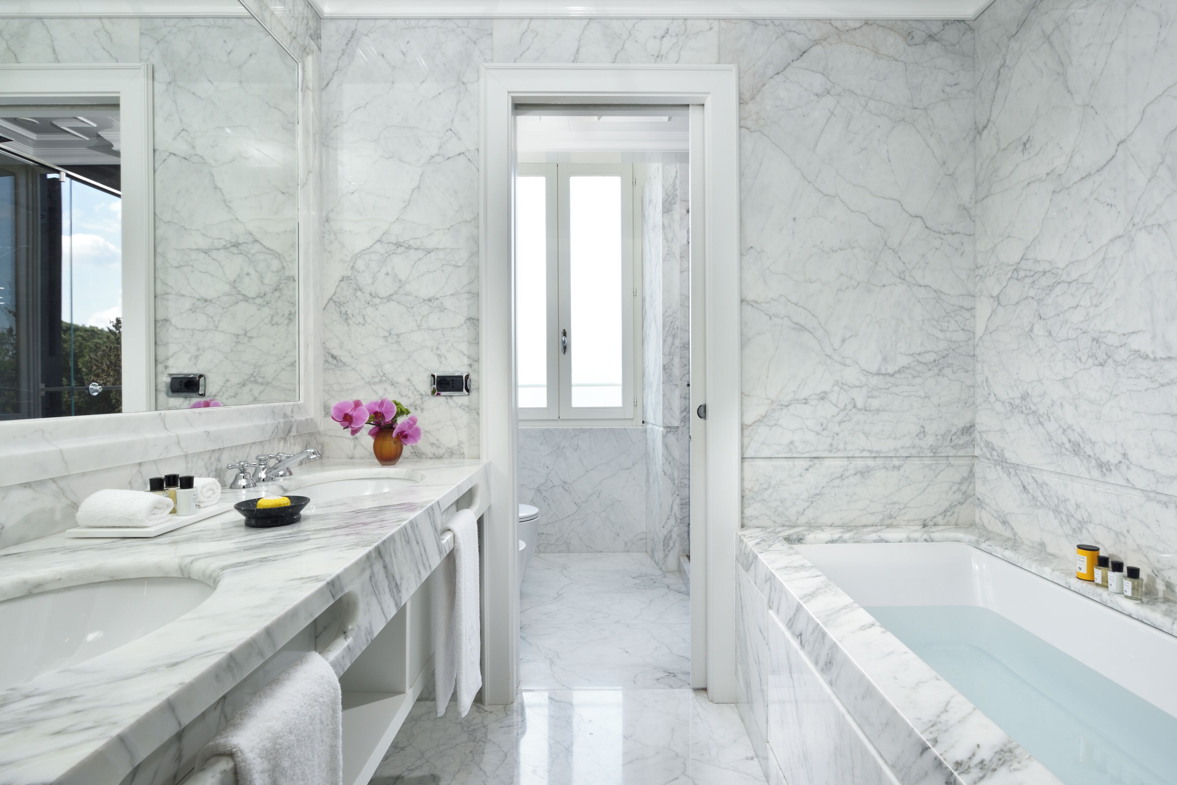 Ein modernes Badezimmer mit Marmorwänden und einer Badewanne.