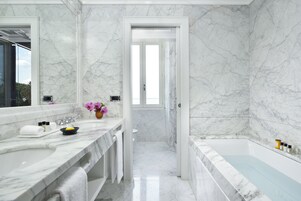 A modern bathroom with marble walls and a bathtub.