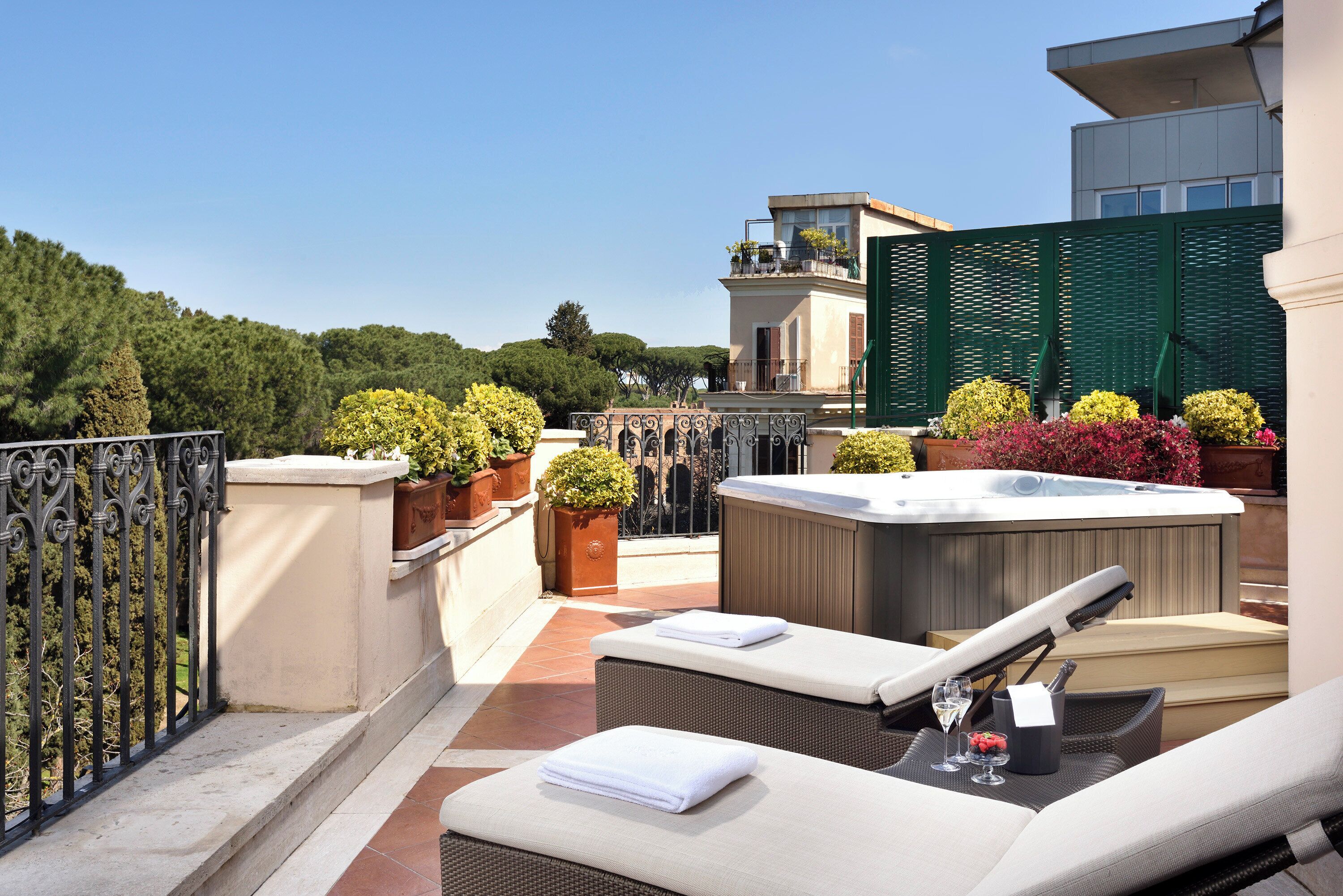 Una terrazza sul tetto con poltrone relax, una vasca idromassaggio e piante in vaso.