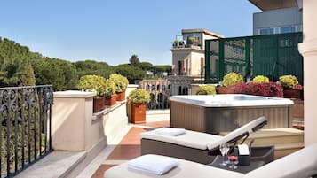 Una terrazza sul tetto con poltrone relax, una vasca idromassaggio e piante in vaso.