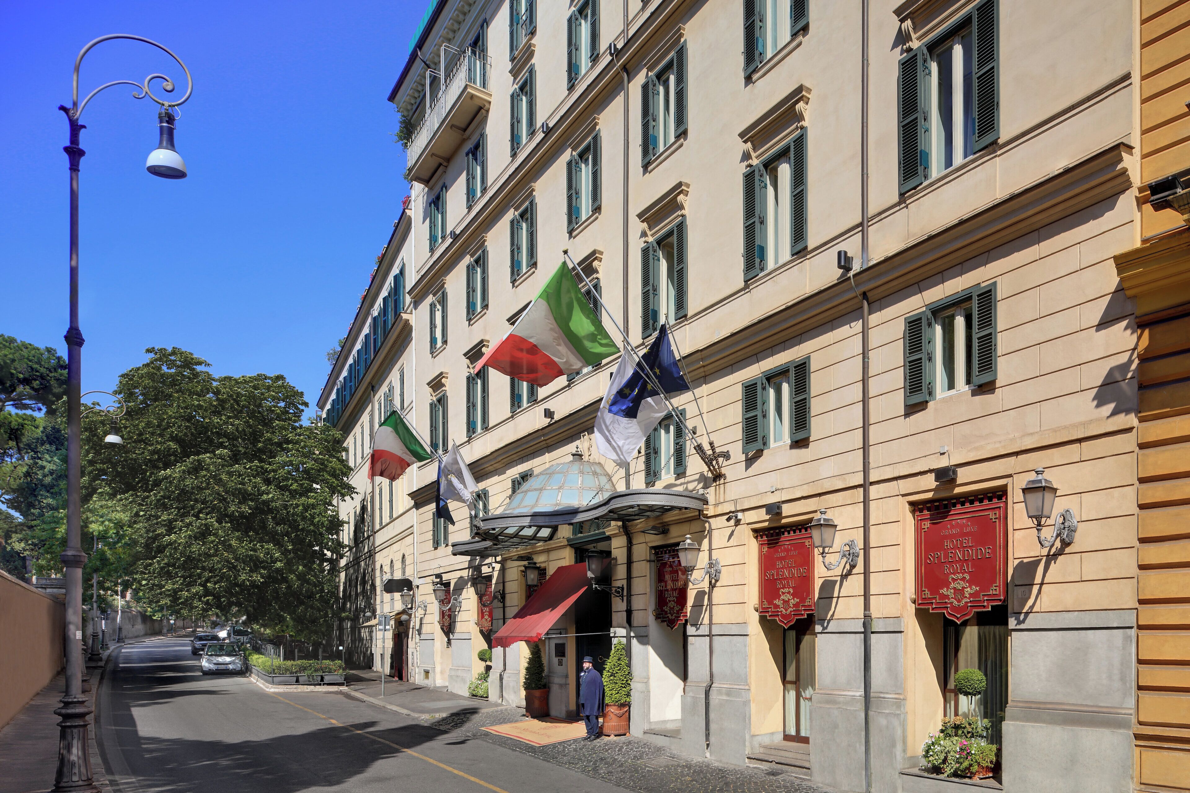 Un hotel con varias banderas, un toldo rojo y un cartel que indica que es un Royal Hotel.
