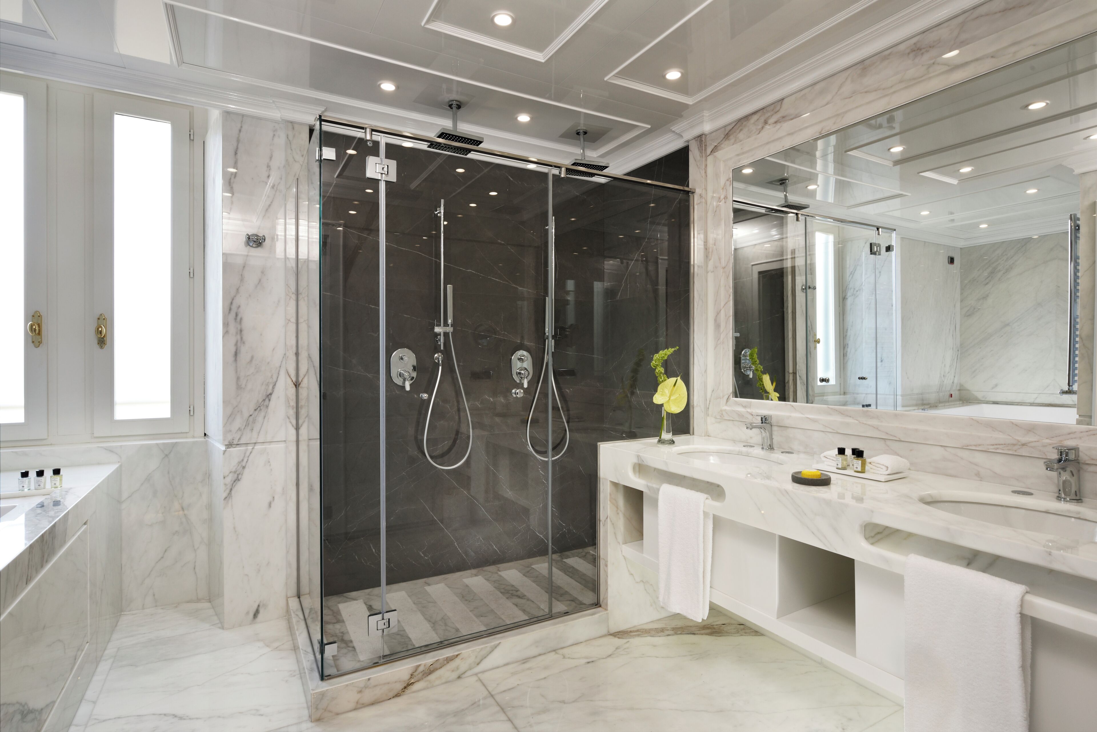 A modern bathroom with a glass-enclosed shower, a large mirror, and a white vanity with a sink.