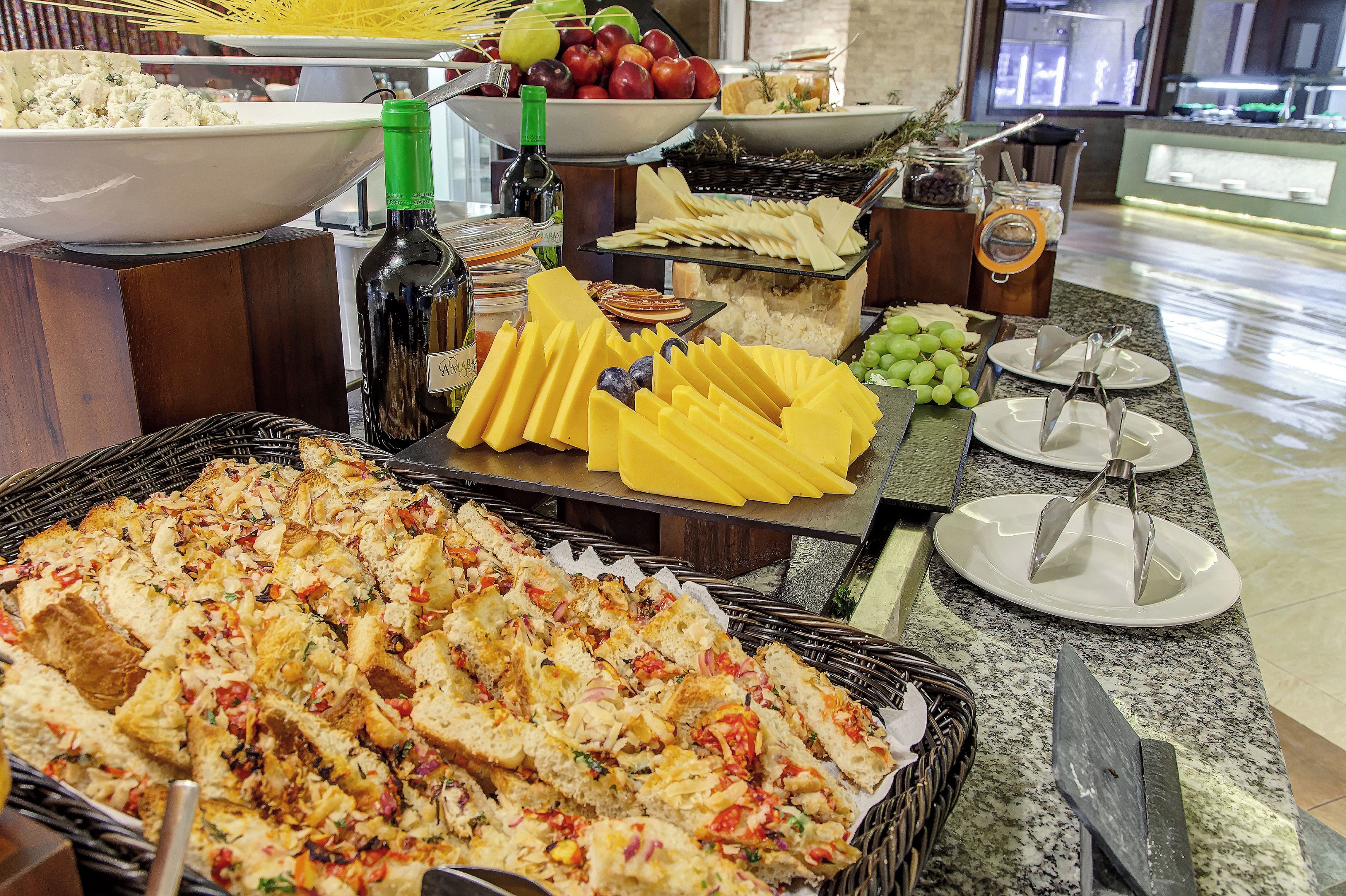 Un buffet con diversi cibi, tra cui formaggio, frutta e pane.