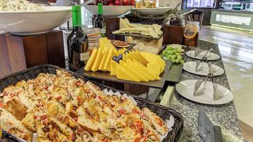 Un buffet con diversi cibi, tra cui formaggio, frutta e pane.