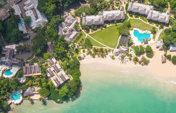 Experience a resort with diverse architecture, multiple pools, and a beach area surrounded by lush greenery.