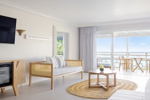 Relax in a spacious room with a sofa, chairs, and a flat-screen TV, offering a serene sea view.