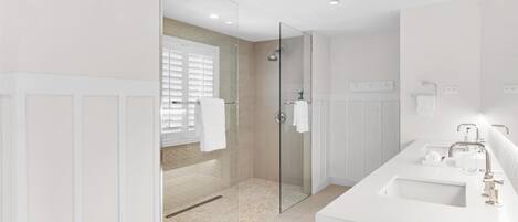 Un baño moderno con ducha de vidrio, lavamanos blanco y un espejo grande.