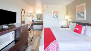 Una habitación de hotel con cama, escritorio con computadora, televisión y microondas.
