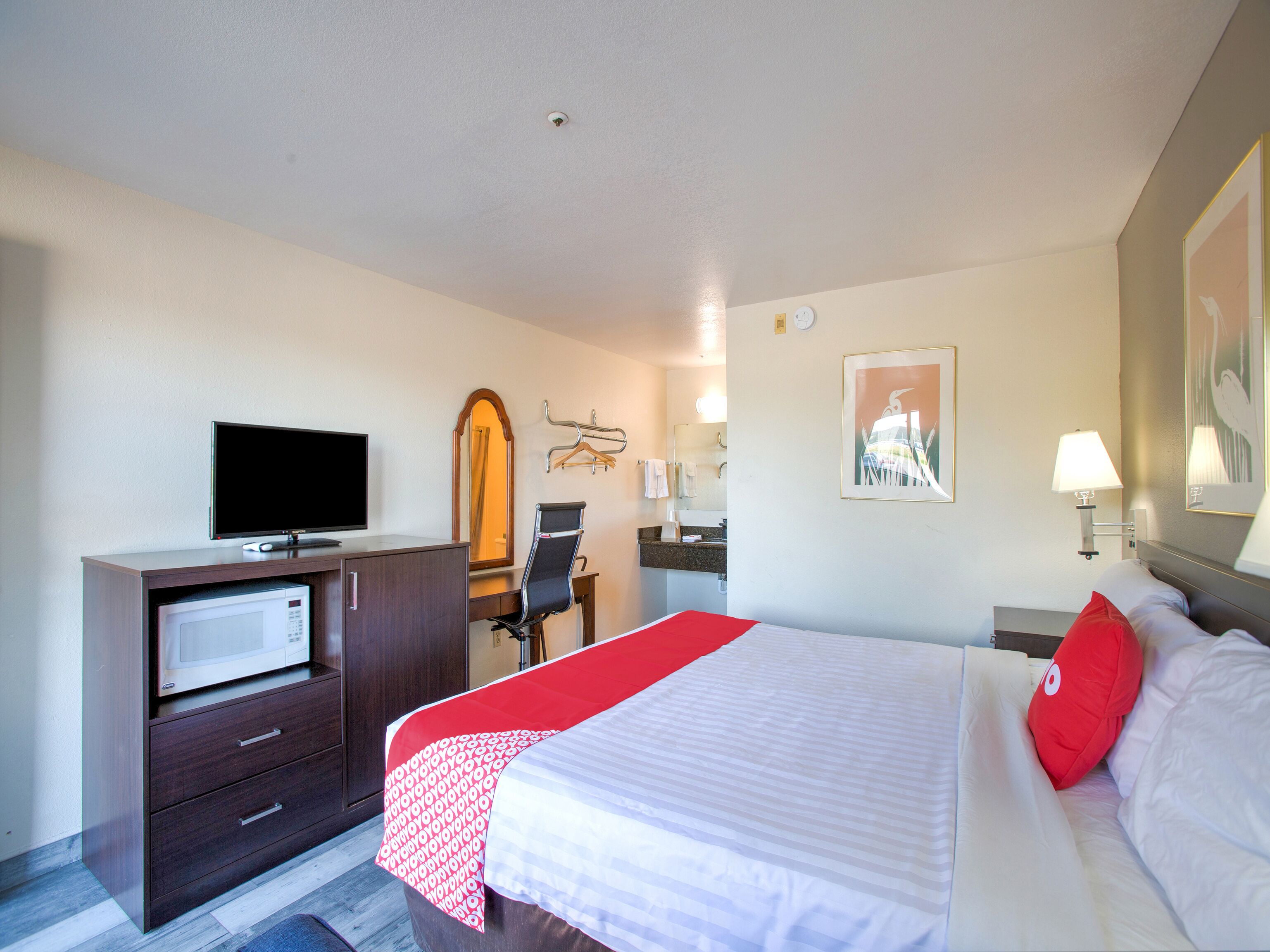Une chambre d’hôtel comprenant un lit, un bureau avec une télévision, un miroir, une chaise et une salle de bain.