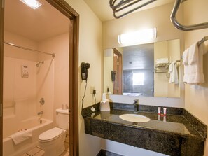 Un baño con lavamanos, espejo, toallero y ducha.