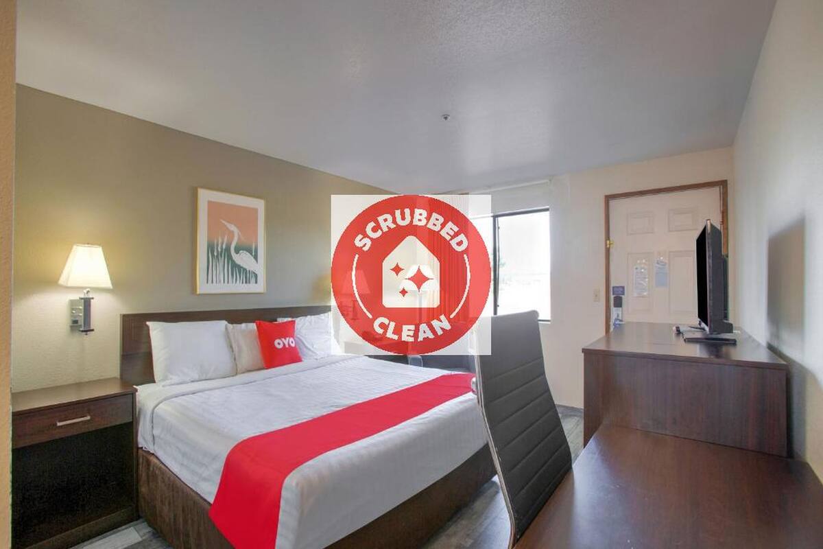 Una habitación de hotel con cama, escritorio, televisor y puerta.