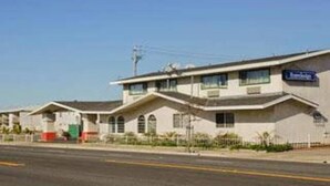 A motel with a simple, single-story structure, a flat roof, and a small parking area in front. - Travelodge Salinas (Salinas)