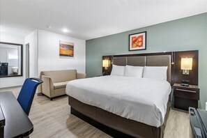 A hotel room with a large bed, a sofa, a desk, and a chair. - Travelodge Salinas (Salinas)