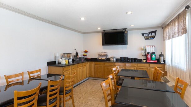 A compact kitchen with wooden cabinets, a black countertop, and a built-in TV. - Travelodge Salinas (Salinas)