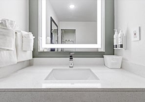 Une salle de bain avec un grand miroir, un lavabo et un porte-serviettes.