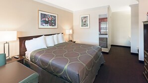 A hotel room with a bed, a desk, a chair, a nightstand, and two framed pictures on the wall. - Travelodge Salinas (Salinas)