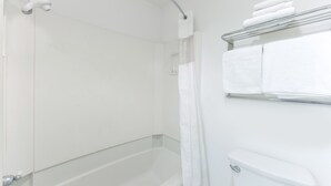 A modern bathroom with a glass-enclosed shower, a white toilet, and a towel rack with folded towels. - Travelodge Salinas (Salinas)