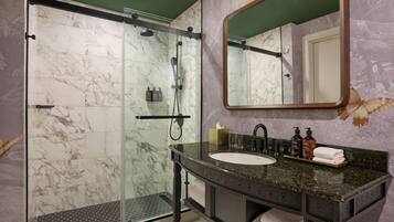 A bathroom with a glass-enclosed shower, a sink with a marble countertop, and a mirror with a butterfly design.
