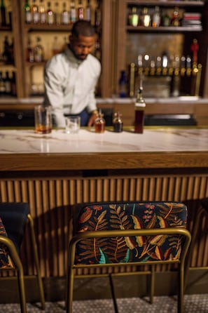 A bar area with a counter, bar stools, and a bartender.