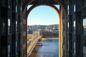 Vista a través de una estructura de ladrillo en arco que da al río, con un puente y edificios al fondo.