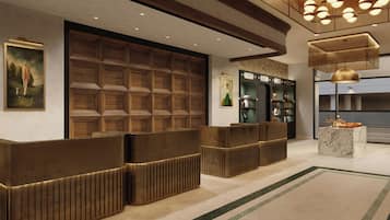A reception area with a wooden reception desk, a framed painting, and a modern chandelier.