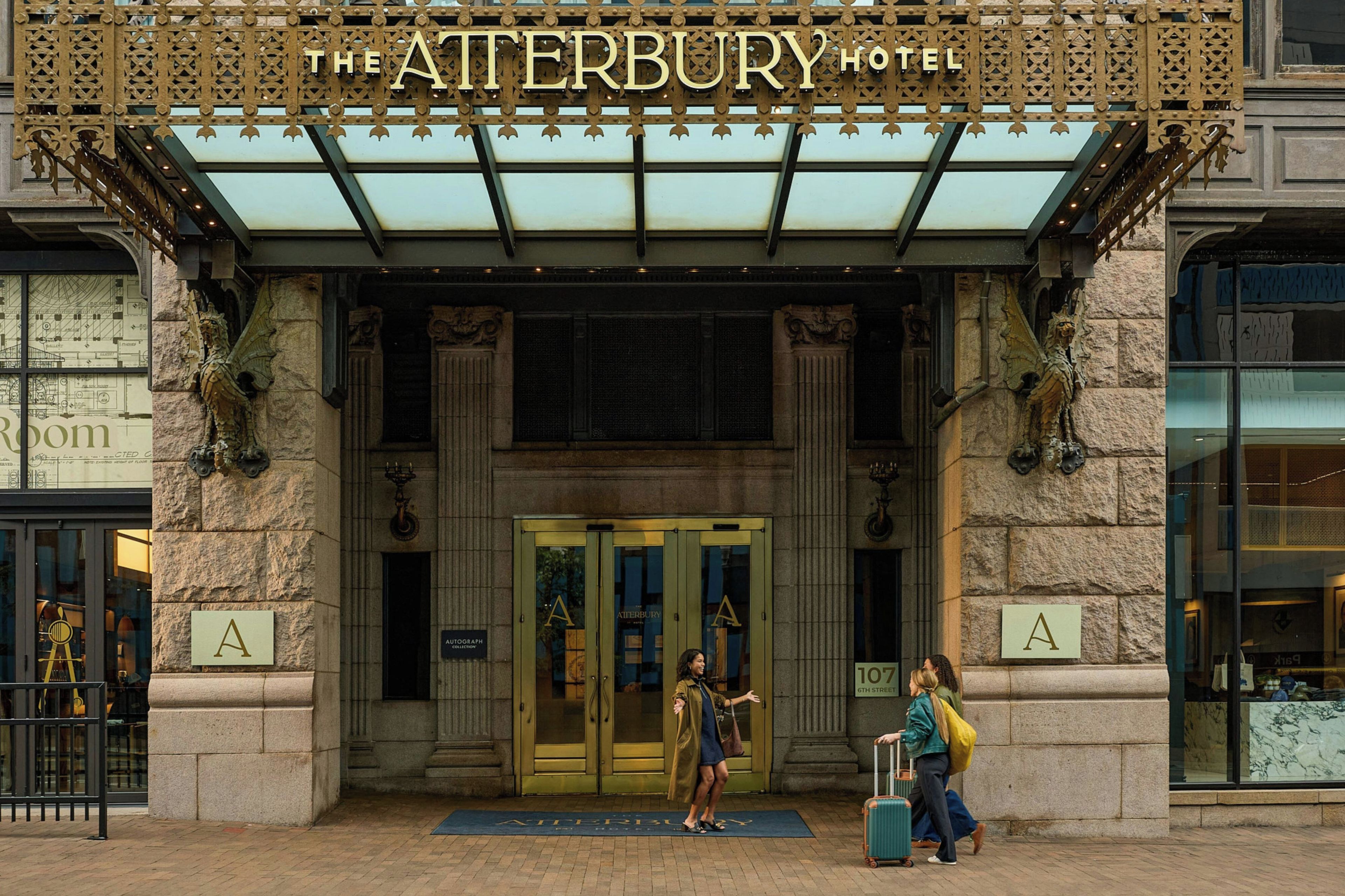 L'ingresso dell'Hotel Atterbury, caratterizzato da un design architettonico classico, con un'imponente entrata dotata di doppie porte e una copertura in vetro.