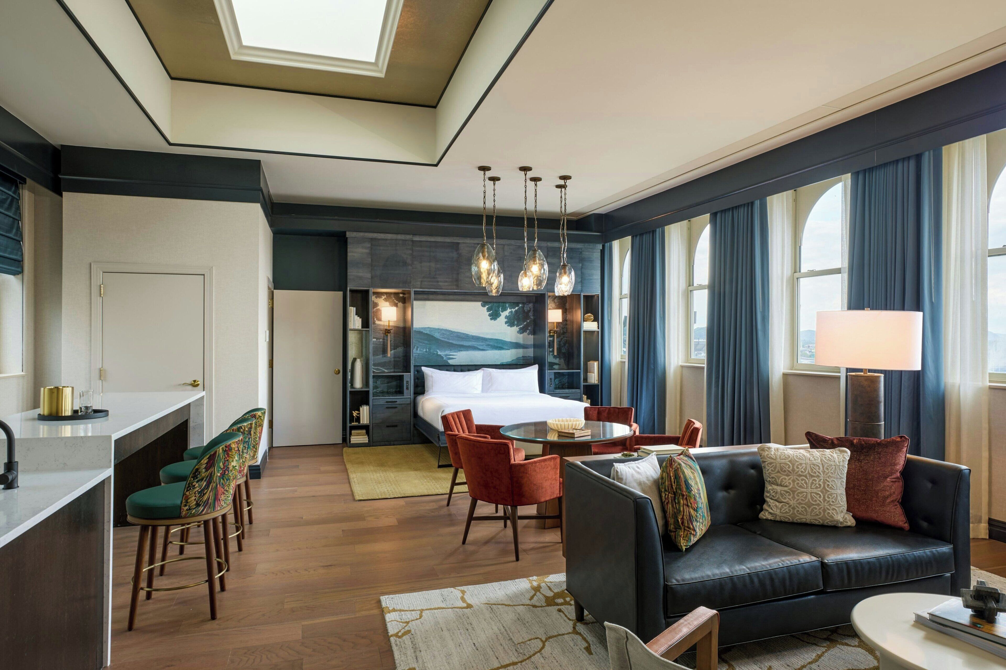 Habitación de hotel con cama, zona de estar, mesa de comedor y kitchenette.