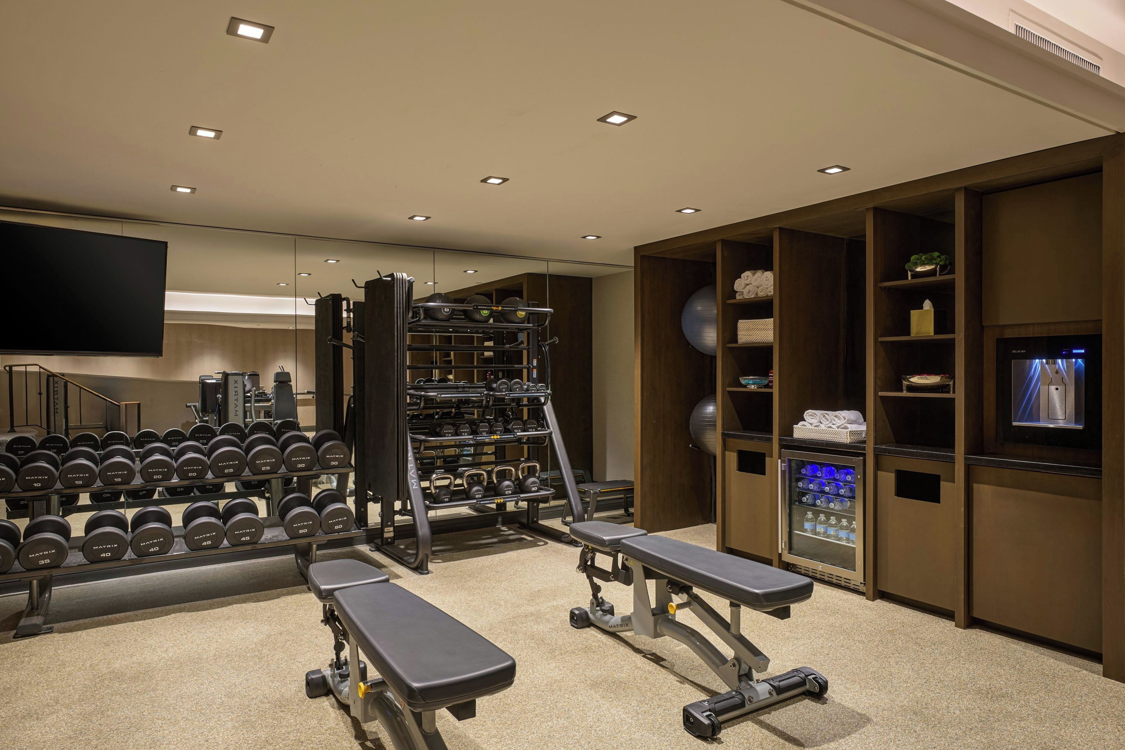 A gym with weightlifting equipment, treadmills, and a water dispenser.
