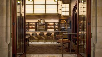 Uma área de bar com balcão, banquetas e diversas garrafas.