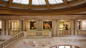 Um interior imponente com teto abobadado, colunas de mármore e obras de arte nas paredes.