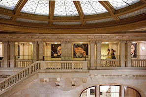 A grand interior with a domed ceiling, marble columns, and a staircase leading to an upper level.