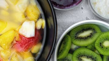 A bowl of fruit salad with pineapple, kiwi, and red fruit.