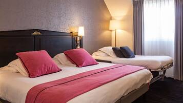 Una habitació d'hotel amb dos llits, cadascun amb capçalera, una taula de nit amb làmpada i una finestra amb cortines.