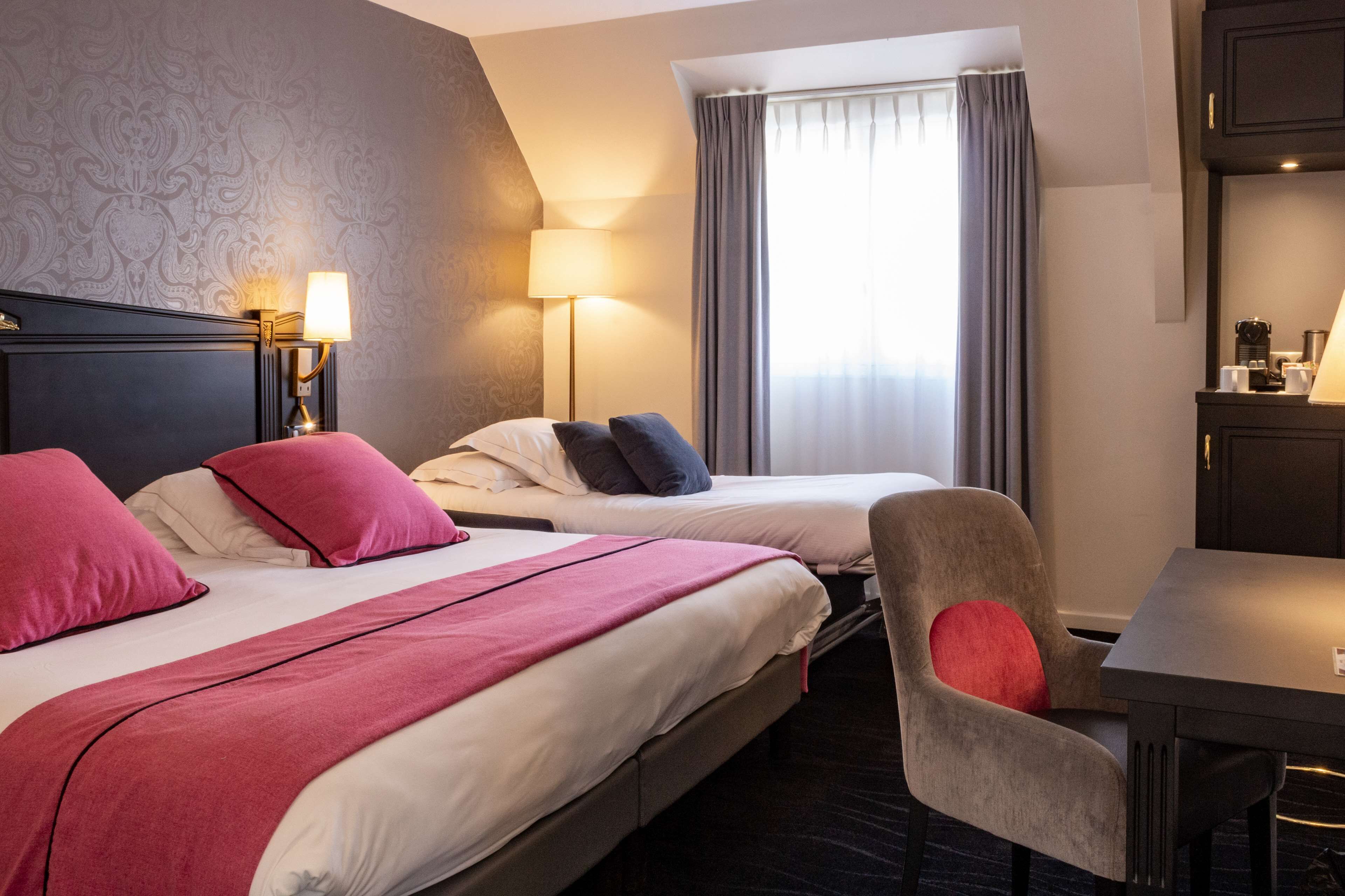 Habitación de hotel con dos camas, un escritorio y una silla.