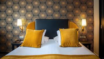 Una habitación de hotel con papel tapiz estampado, una cama con dos almohadas y dos lámparas de noche.