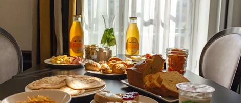 A breakfast table with various food items, including pastries, bread, and a drink.