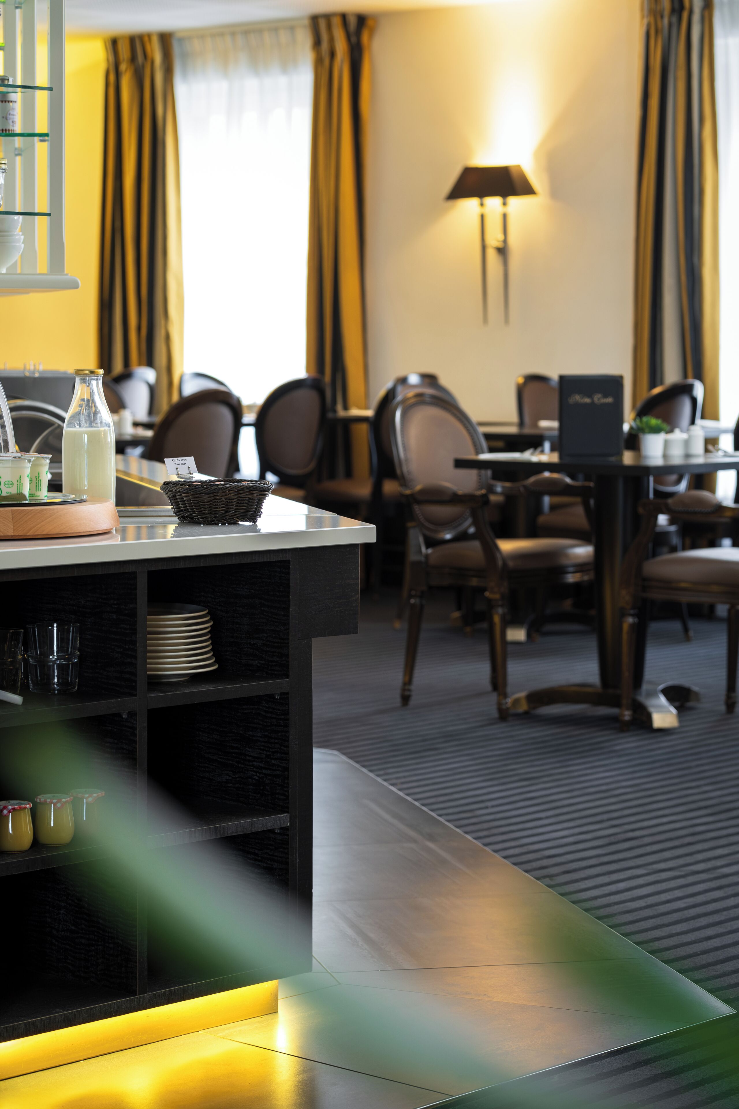 Zona de dinar d'hotel amb un sistema de menjar a la cafeteria, incloent un taulell amb una cistella, una làmpada i un suport per als menús.