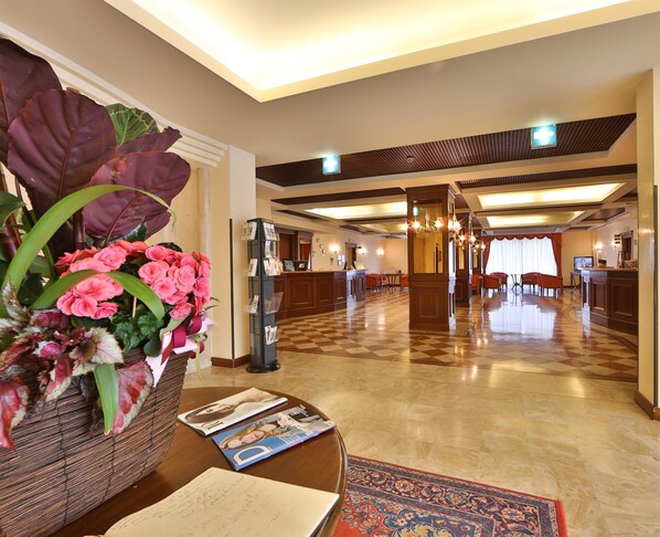 Un vestíbulo de hotel con una recepción, zona de estar y un arreglo floral decorativo.