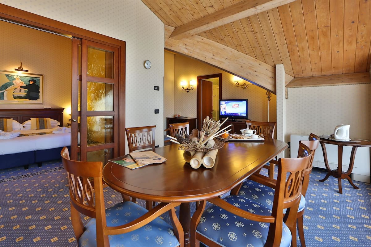 Habitación de hotel con cama, una mesa de comedor con sillas, televisión y un adorno decorativo.