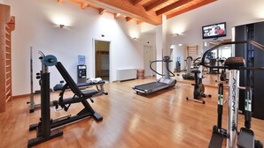 A gym with wooden beams, exercise equipment, and a television on the wall. - Best Western Classic Hotel (Reggio nell'Emilia)