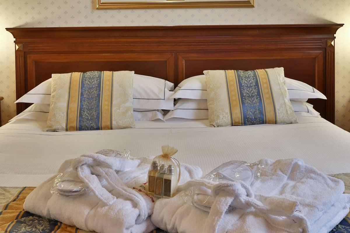 Habitación de hotel con una cama grande, dos almohadas, un cuadro sobre la cama y un juego de toallas sobre la cama.