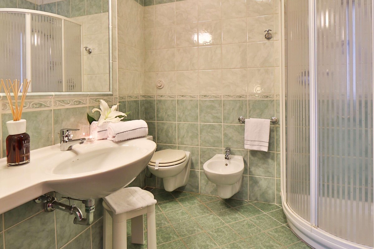 Un baño con lavamanos, espejo, inodoro, bidé y cabina de ducha.