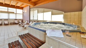 A spa area with a hot tub, wooden chairs, and a tiled floor. - Best Western Classic Hotel (Reggio nell'Emilia)