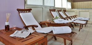 A spa room with wooden chairs, white towels, a newspaper, a candle, and a vase with flowers. - Best Western Classic Hotel (Reggio nell'Emilia)