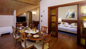 A dining area with a wooden table and chairs, a television, and a bed with a painting in the background. - Best Western Classic Hotel (Reggio nell'Emilia)
