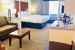 Una habitación de hotel con cama, escritorio, sofá y baño con lavamanos.