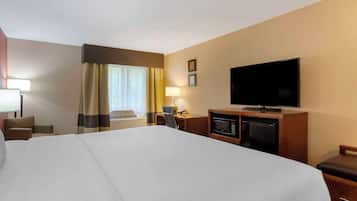 A hotel room with a large bed, a television, a desk with a chair, a microwave, and a small refrigerator.