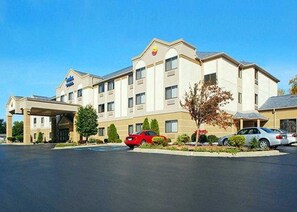 A hotel with a central entrance, multiple floors, and a parking lot with cars.