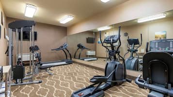A hotel gym with treadmills, elliptical machines, and weight equipment.